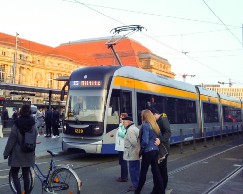 Straßenbahn mit Fußgängern vor dem Hauptbahnhof Leipzig
