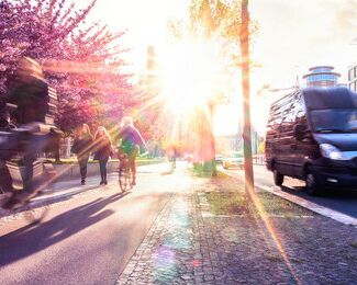 Fahrradfahrer im Sonnenlicht, Autobus und Straßenbahn