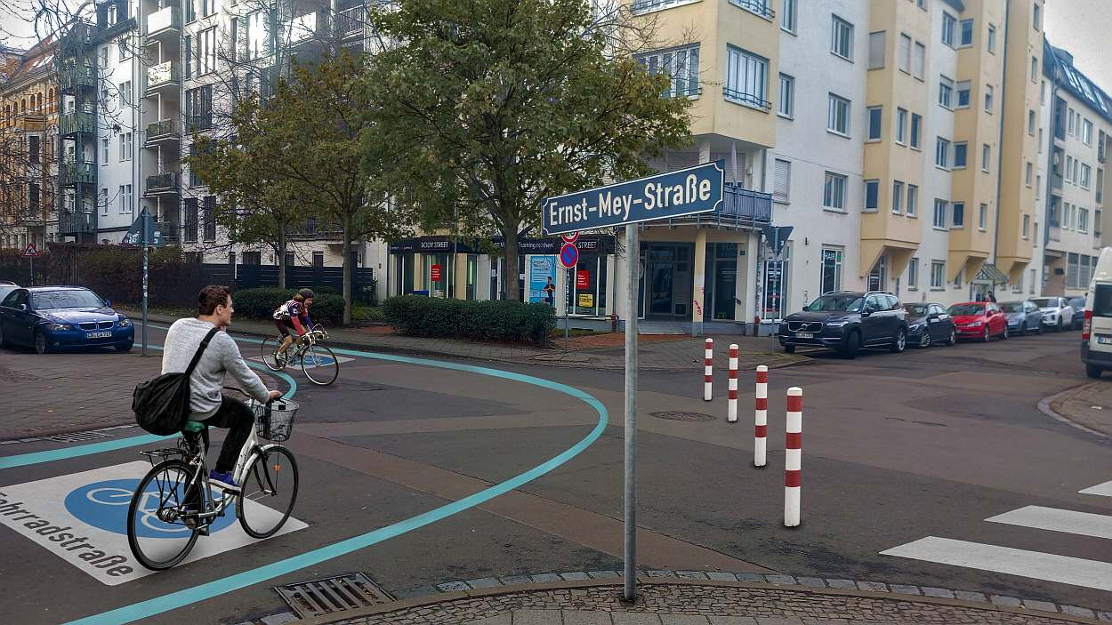 Diagonalsperre aus Pollern an der Kreuzung Nonnenstraße, Ernst-Mey-Straße. Radfahrer auf blau markierter Fahrradstraße mit parkenden Autos und mehrstöckigen Gebäuden
