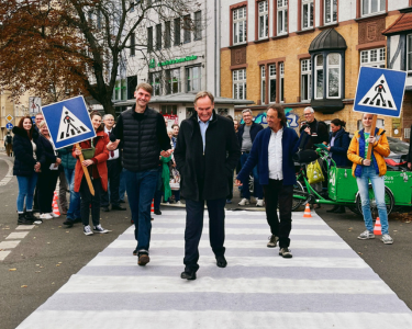 Gruppe von Personen überquert eine Straße mit Schildern in der Hand auf einem ausgerollten Zebrastreifen in Leipzig-Connewitz - darunter OBM Jung und Ökolöwen-Geschäftsführer Tino Supplies.