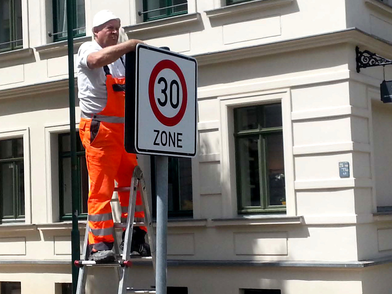 Bauarbeiter stellt neues Tempo 30 Schild auf.