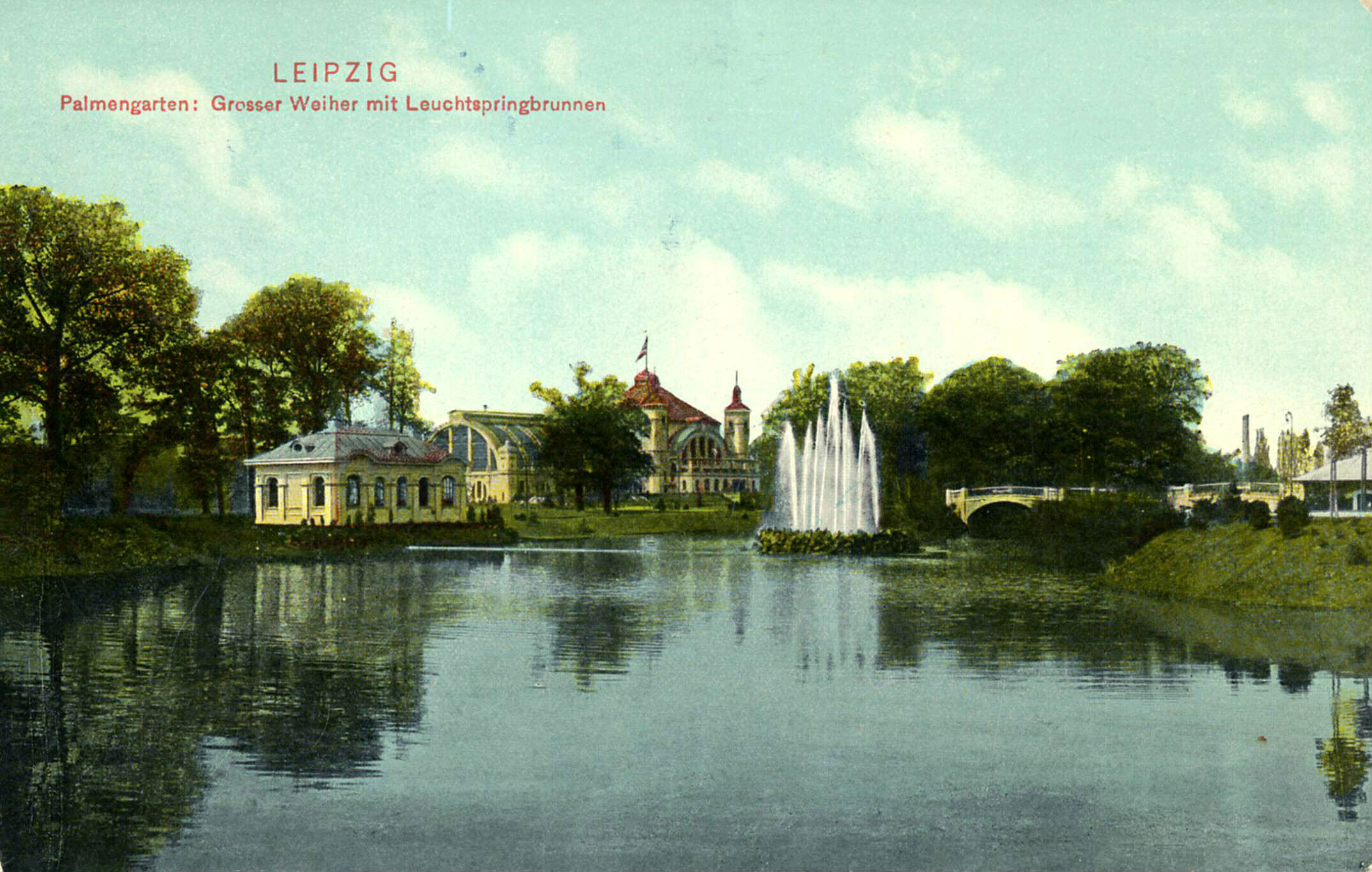 Großer Teich mit Springbrunnen und Gebäuden im Palmengarten Leipzig umgeben von Bäumen